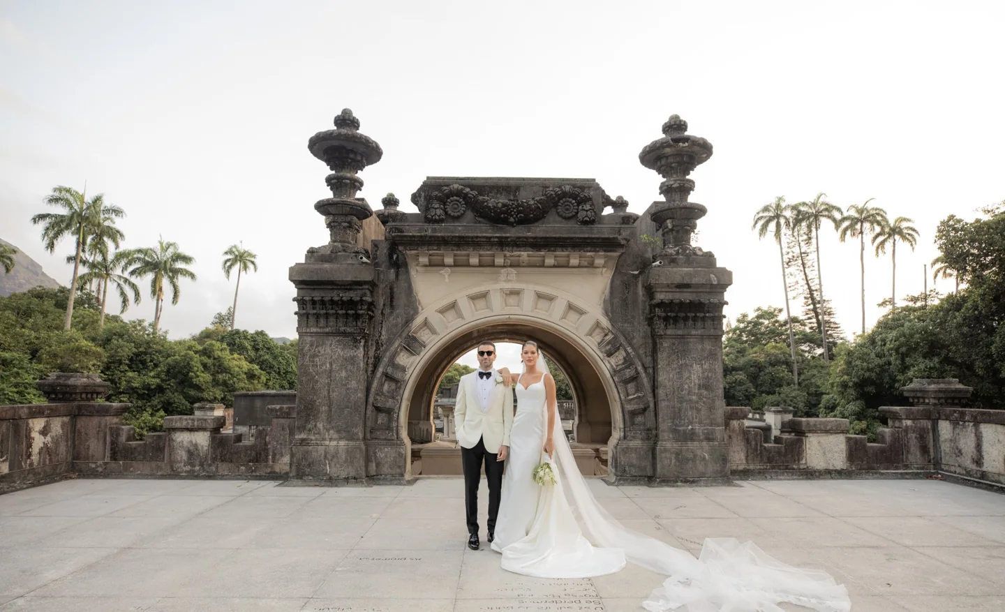 Bride and groom beneath the Parque Lage arch